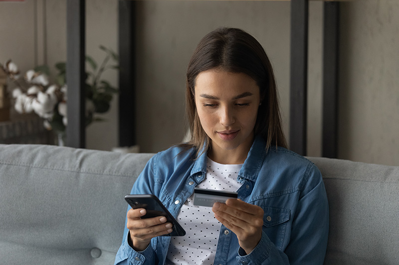 Mujer mirando su celular y tarjeta
